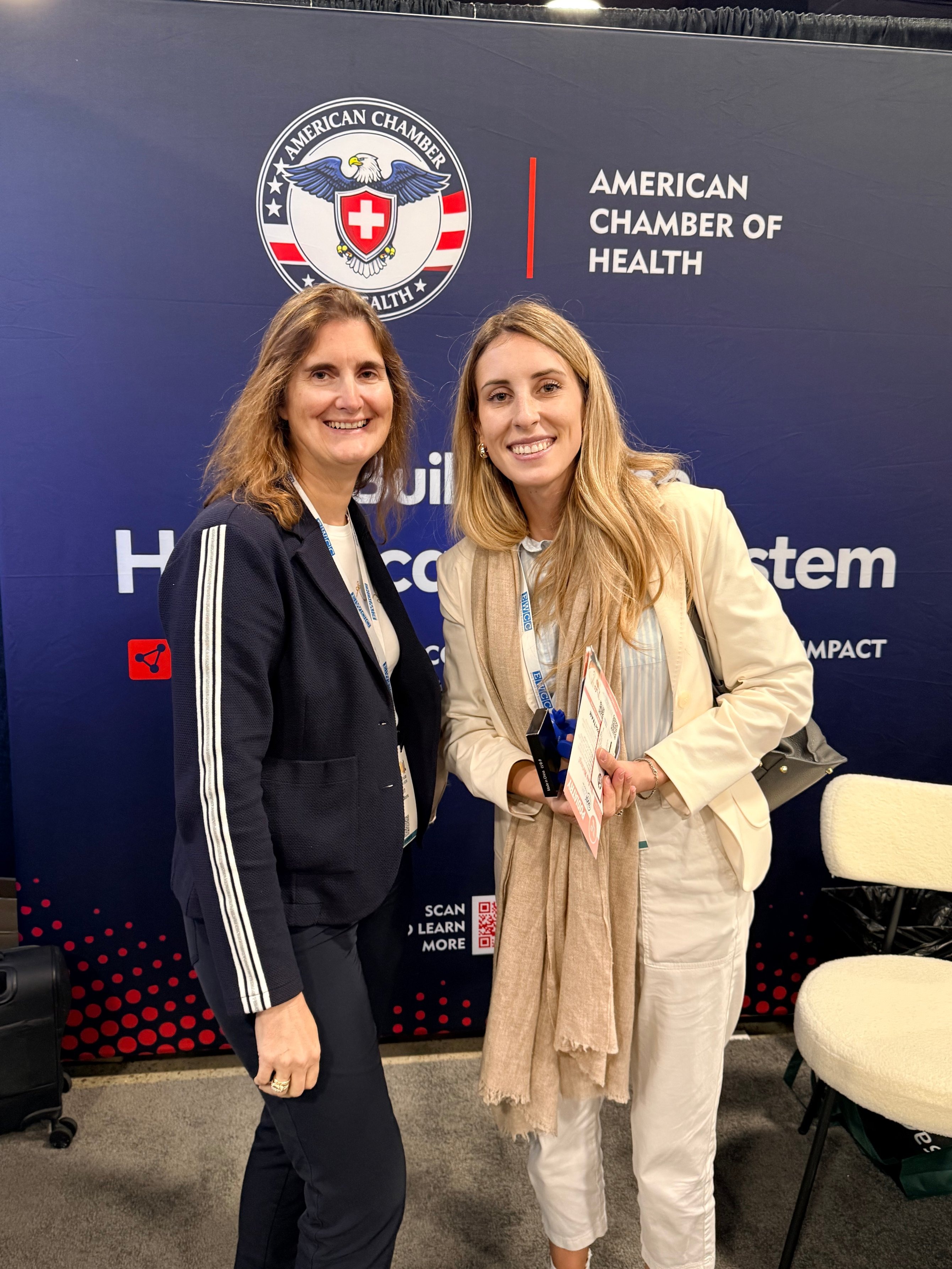 Two attendees posing with brochures at the ACH backdrop in Nashville