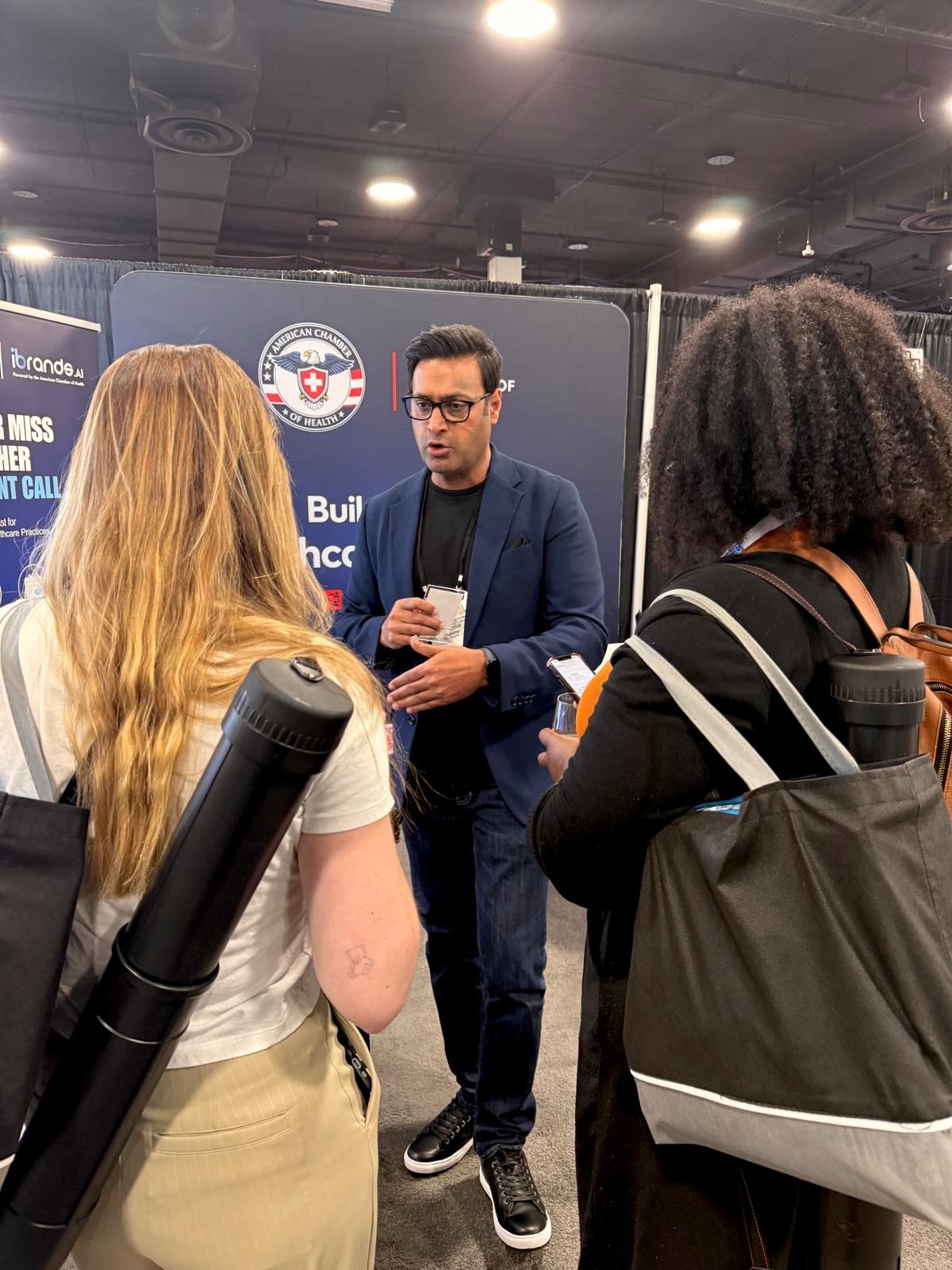 Khalid Sattar speaking with two attendees at the ACH booth