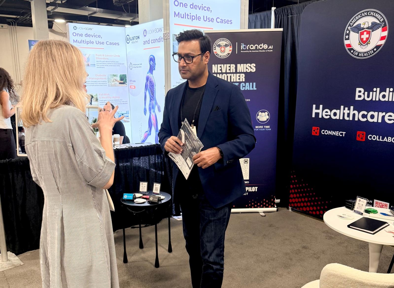 Khalid Sattar talking with an attendee beside the MovnScan device booth