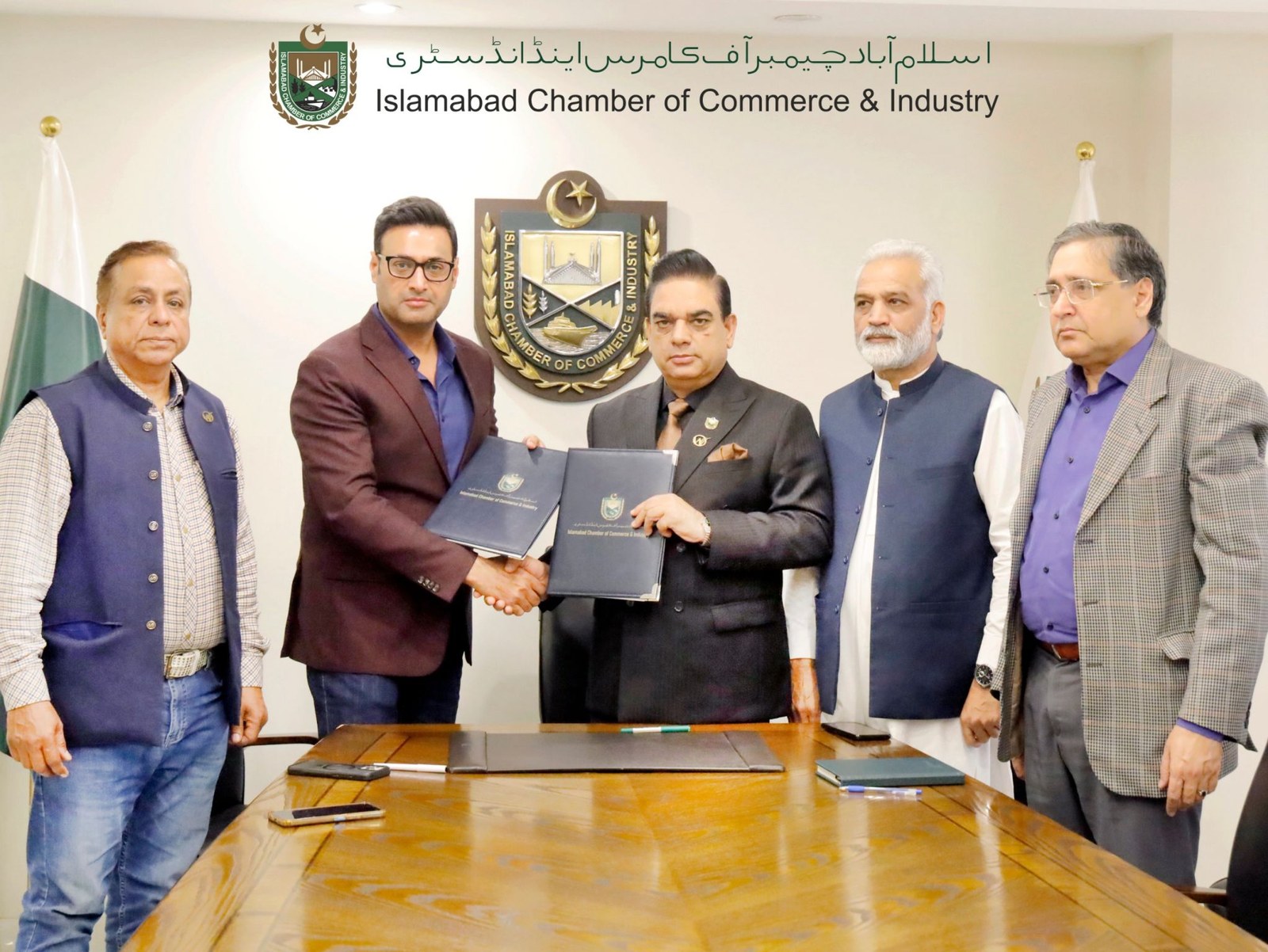 Muhammad Khalid and the ICCI official shake hands after the signing