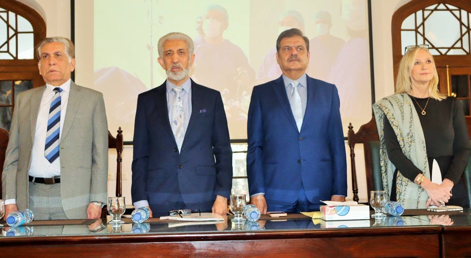Four speakers pose behind the dais at the KEMU conference